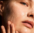 Close-up of a person's face with a hand gently touching the cheek, highlighting skin texture.